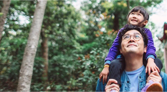 child on man's shoulder's in a forest