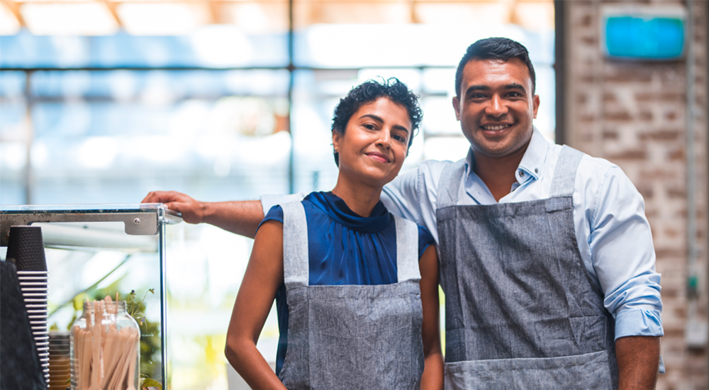 Smiling couple standing at the counter of their small business enterprise.