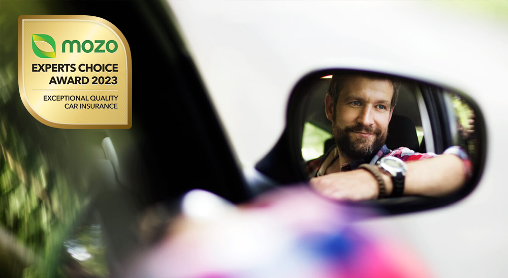 Male driver's reflection in side mirror of car