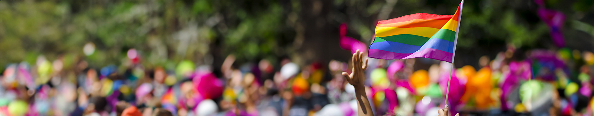  People marching with a large rainbow flag in a Gay Pride parade