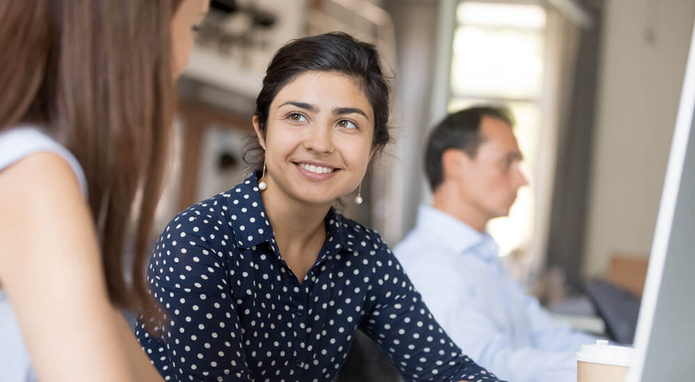 Multiracial colleagues communicating sitting in office at the desk