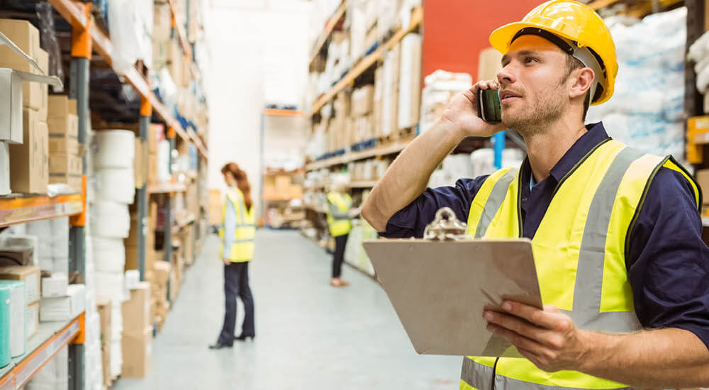 Warehouse worker talking on phone holding a clipboard