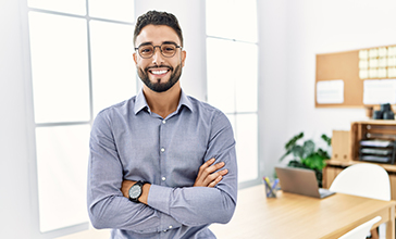 Smiling young man leaning on his work desk