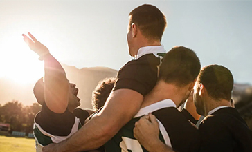 Rugby players lifting teammate after winning