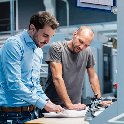 Two men standing at table discussing document