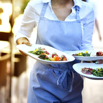 Hospitality worker carrying three plates of food