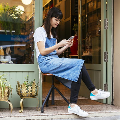 Woman outside shop on phone using social media for business