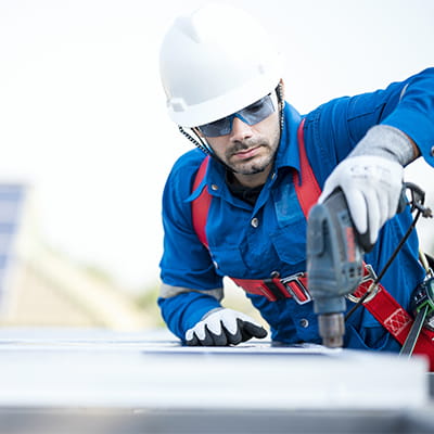 Workman on drilling on rooftop wearing safety attire