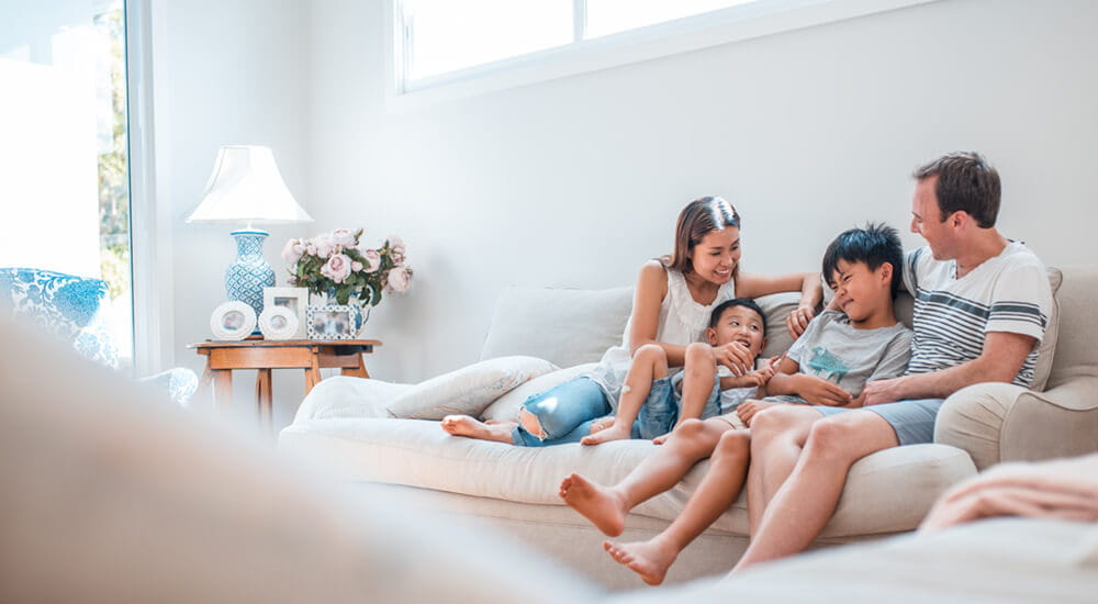 Contents Insurance banner - Young family sitting on the sofa together in their home