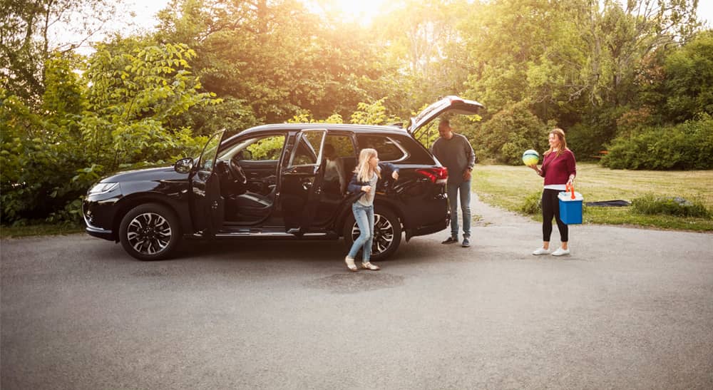 Motor vehicle insurance banner of family getting out of a car in a park