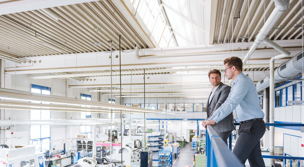 Property quote info guide banner - Two men standing on gangway overlooking a warehouse