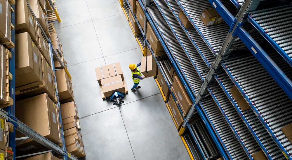 Worker in hi-vis stacking cardboard boxes in a warehouse