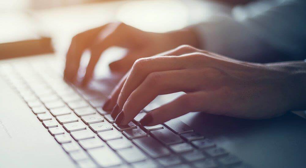 Close up of female hands resting on a keyboard