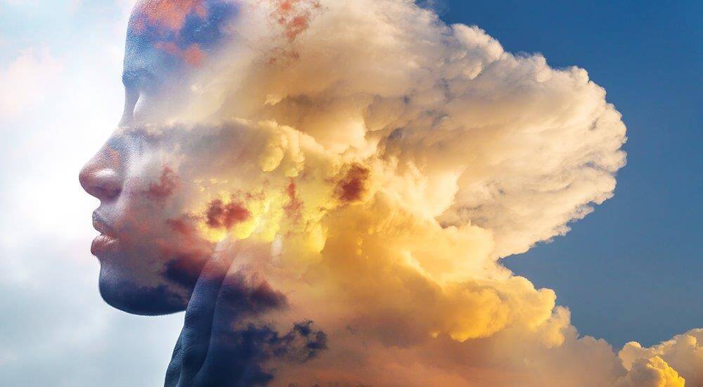 Double exposure of woman and cloudy sky