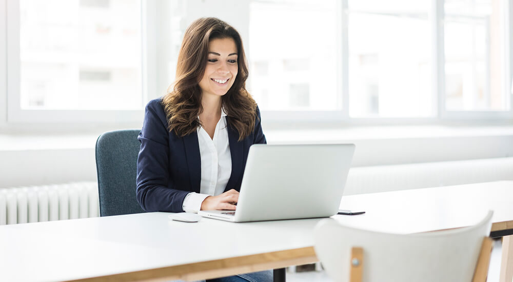 Young, smiling woman working at laptop