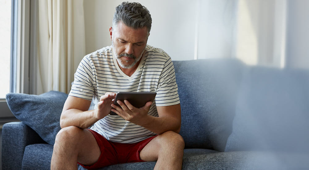 Concentrated man using digital tablet at home