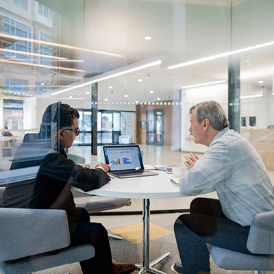 Two men in office discussing graph on laptop computer