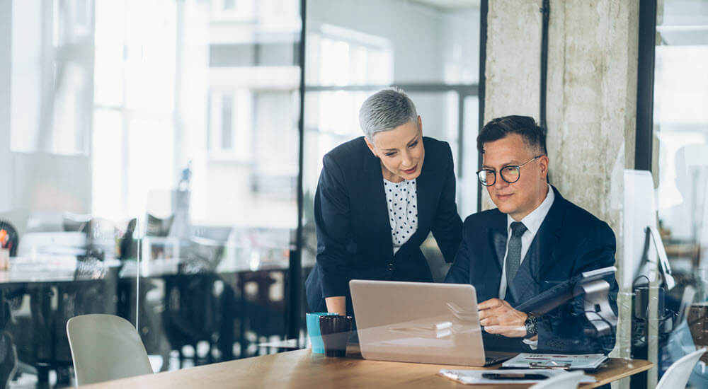 Businessman and business woman working together at the office using laptop and documents