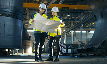 Male and female managers discussing over document at construction site