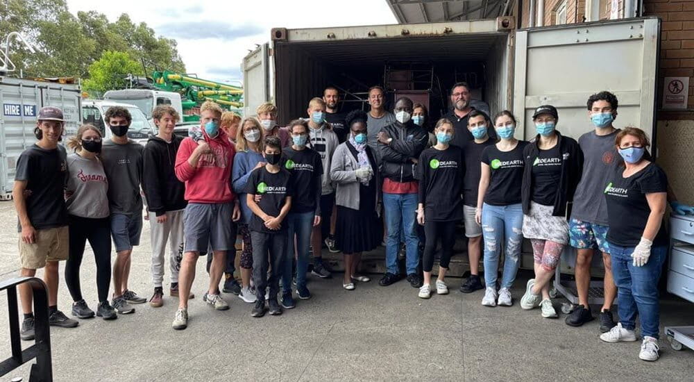 MedEarth volunteers standing outside a 40-foot container packed with medical supplies