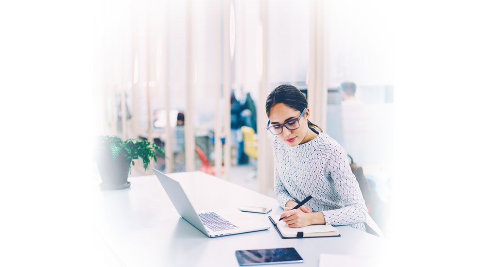 QBE Leadersip webinar series - pivot or perish - young woman writing in notebook sitting at laptop