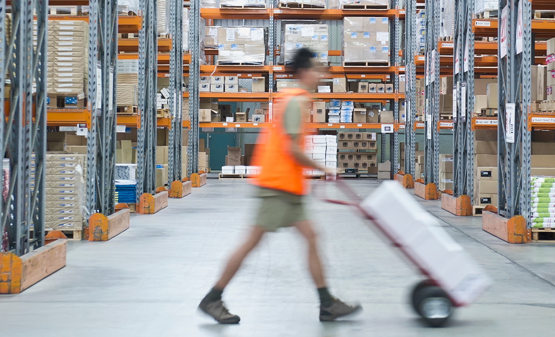 Man pushing loaded trolley through warehouse