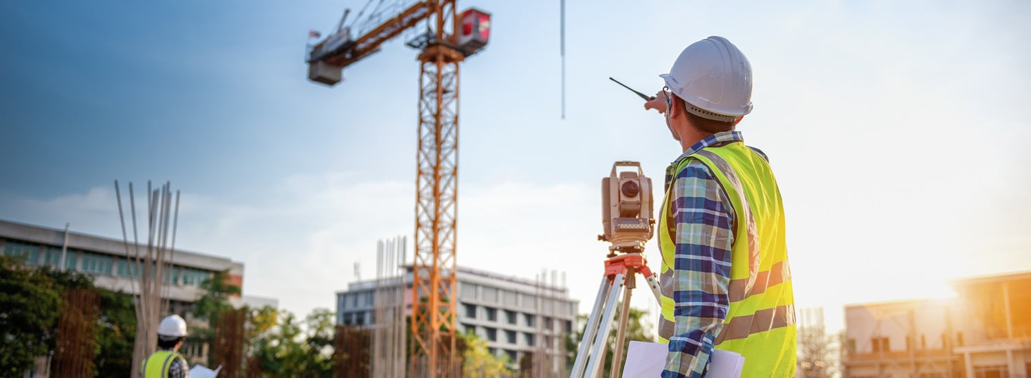 Construction worker on work site with crane in the background