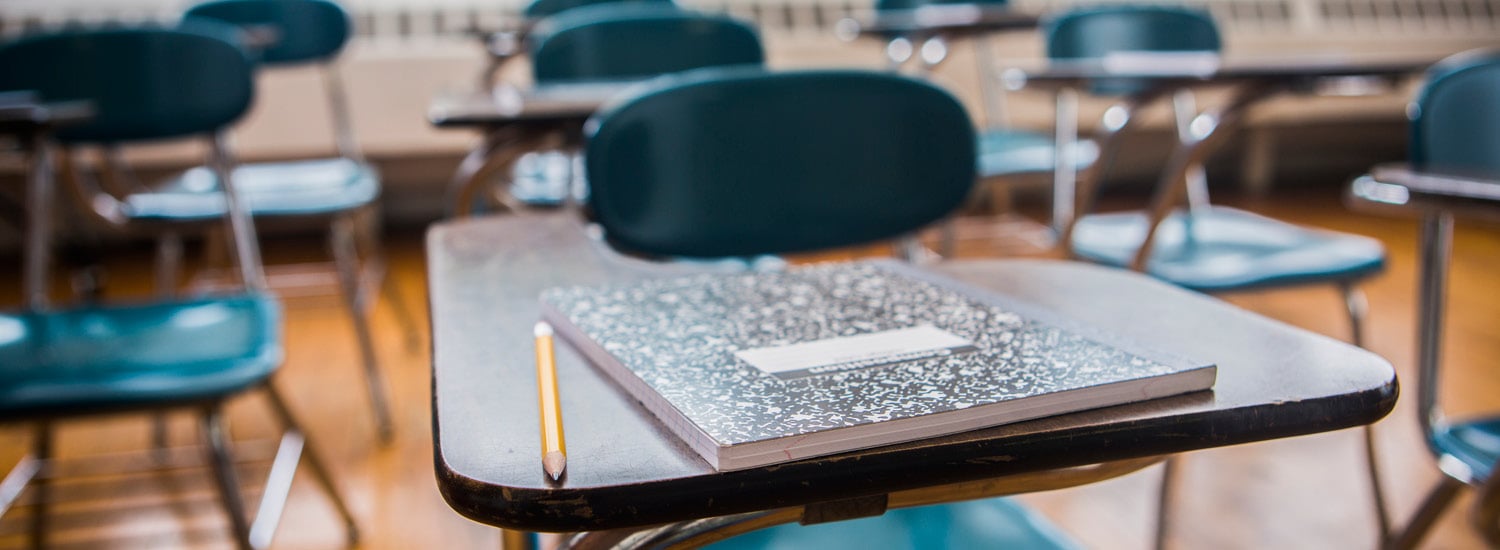 Close up of pencil and writing pad on school desk in a classroom