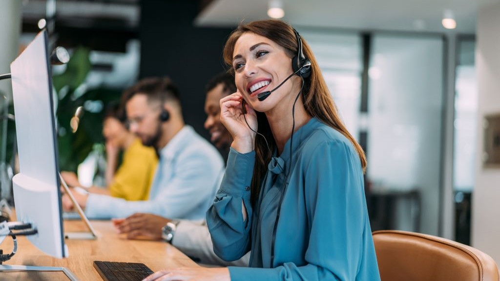 A female call centre worker smiling while talking into her headset