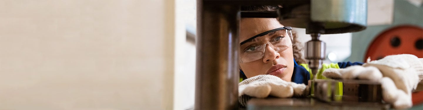 Close up of woman wearing goggles while using machinery in workshop