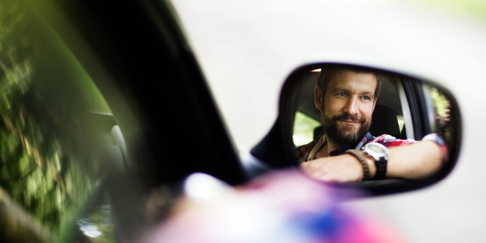 Young man reflected in a car side mirror