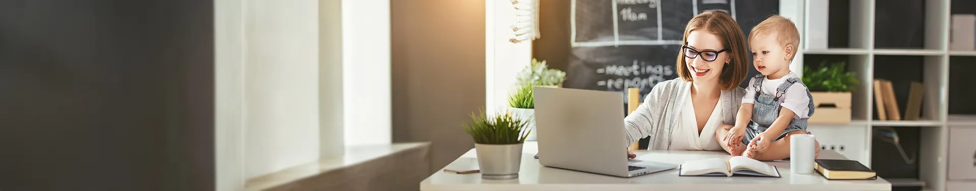 Mother with daughter sitting at table with laptop