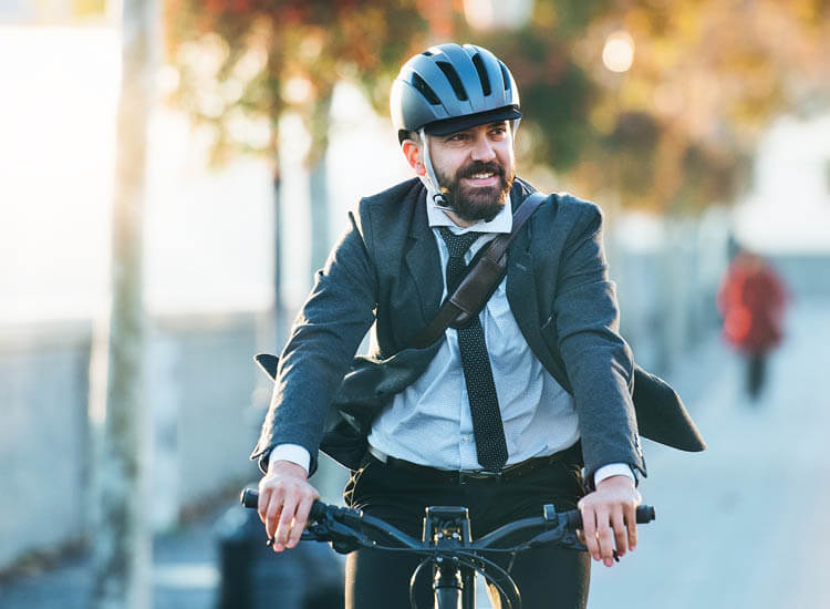Businessman commuter with electric bicycle traveling home from work in city