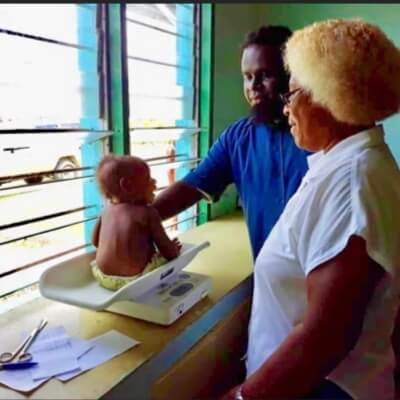 Med Health - medical workers weighing a young child