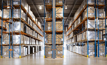 Rows of shelves with goods boxes in huge distribution warehouse at industrial storage factory.