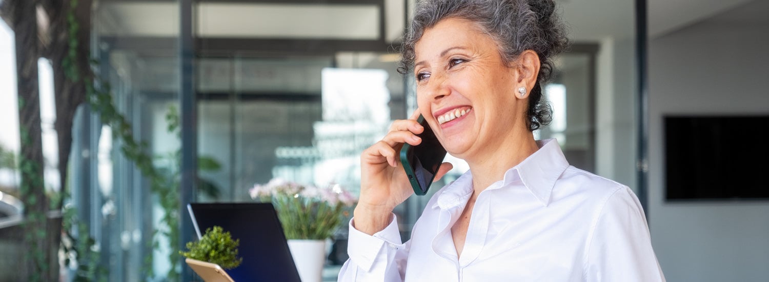 Female office worker smiling while talking on phone at work