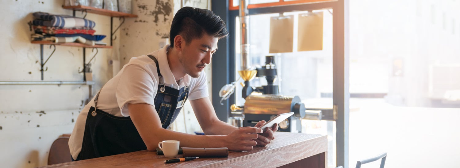 Male hospitality worker reading notes at a counter