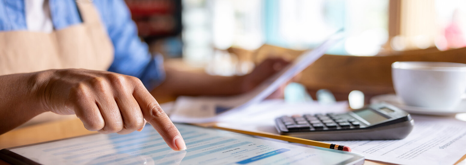 Close-up on a small business owner doing the accountancy at a cafe using a tablet computer