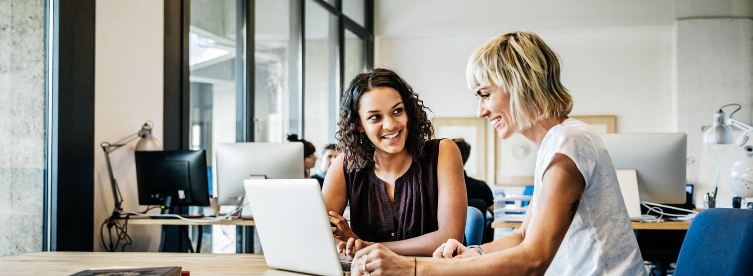 Two casual dressed businesswomen talking in a meeting with laptop