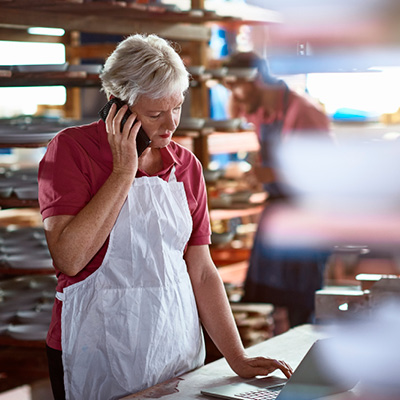 Hospitality worker talking on her mobile phone while looking at her laptop