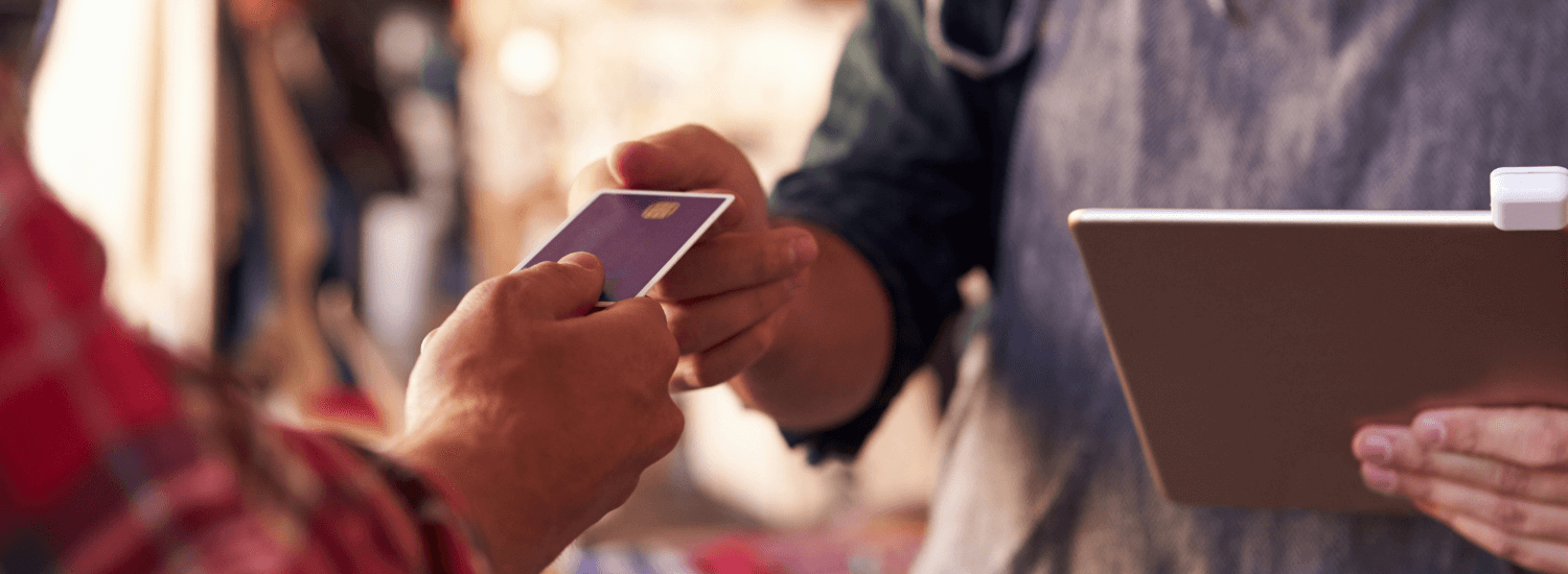 Close up of sales assistant with credit card reader on digital tablet accepting a customer's credit card