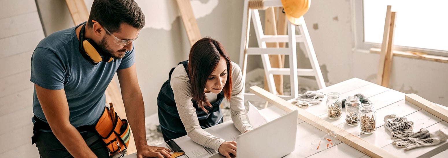 Couple on worksite viewing laptop on table
