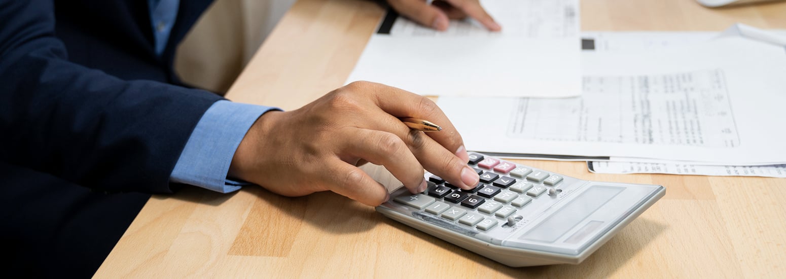 Businessman working on desk office using a calculator to complete his tax audit