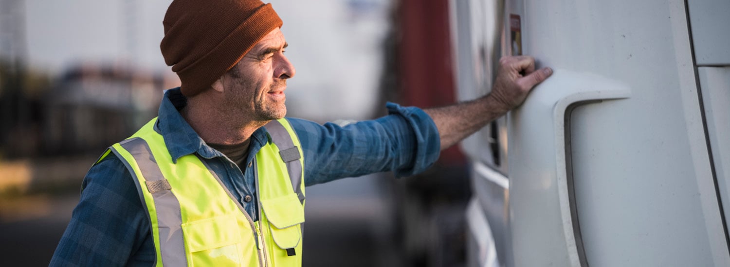 Male tradesperson standing next to vehicle