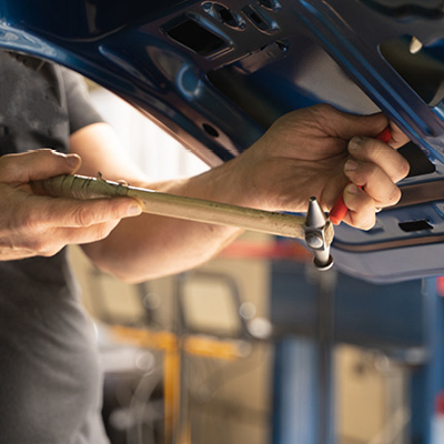 Close up of car mechanic fixing the hail damage on a car panel