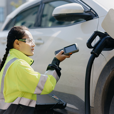 Close up of woman wearing hi-vis repairing electric vehicle