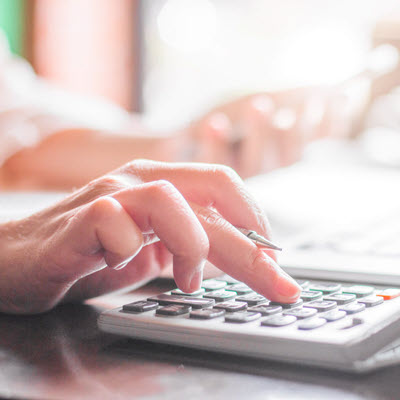 Close up of woman's hand using calculator to check her insurance premium