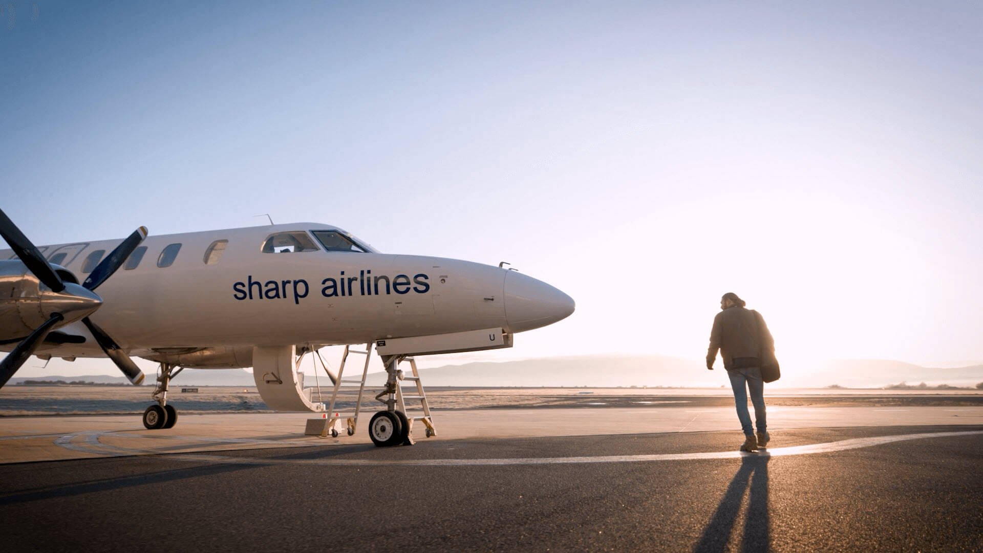 Male passenger crossing the tarmac to a waiting sharp airlines plane