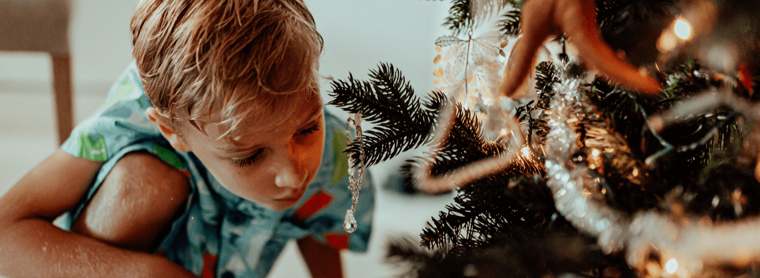Young boy crouching by a decorated Christmas tree