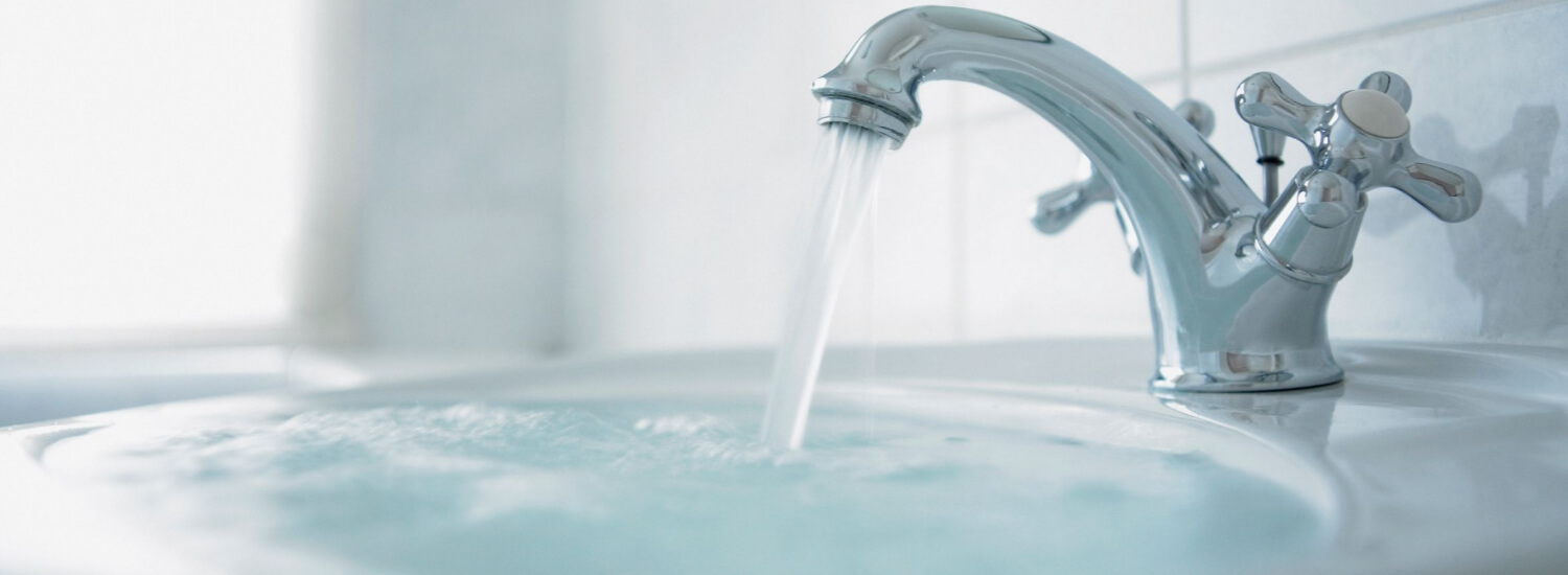 Close up of running tap and overflowing basin